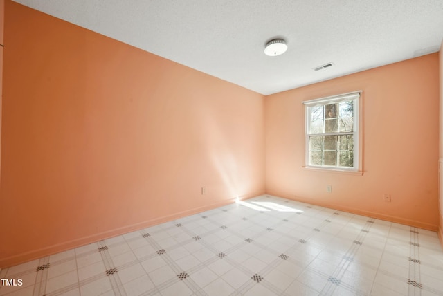 spare room featuring visible vents, a textured ceiling, baseboards, and tile patterned floors