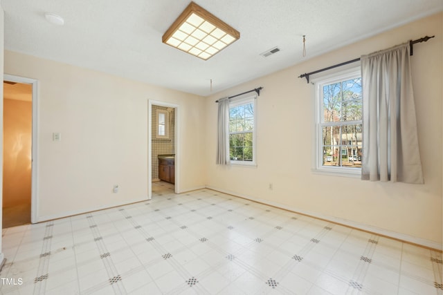 unfurnished bedroom with baseboards, a textured ceiling, visible vents, and tile patterned floors