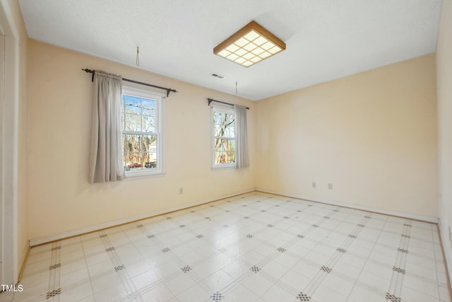 spare room featuring baseboards, visible vents, and tile patterned floors