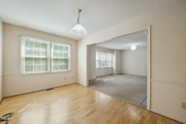 spare room featuring a textured ceiling, wood finished floors, and visible vents