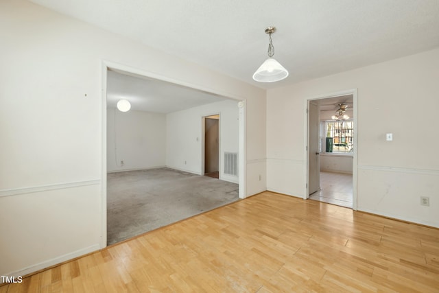 empty room with baseboards, visible vents, and wood finished floors