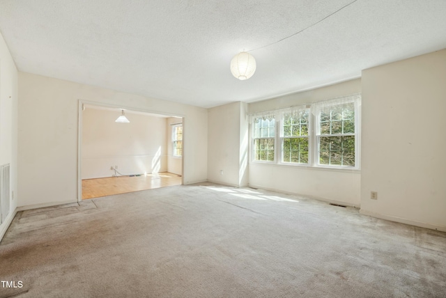 carpeted spare room featuring visible vents and a textured ceiling