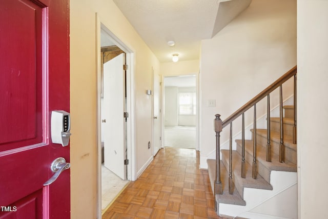 foyer entrance featuring stairs, baseboards, and a textured ceiling