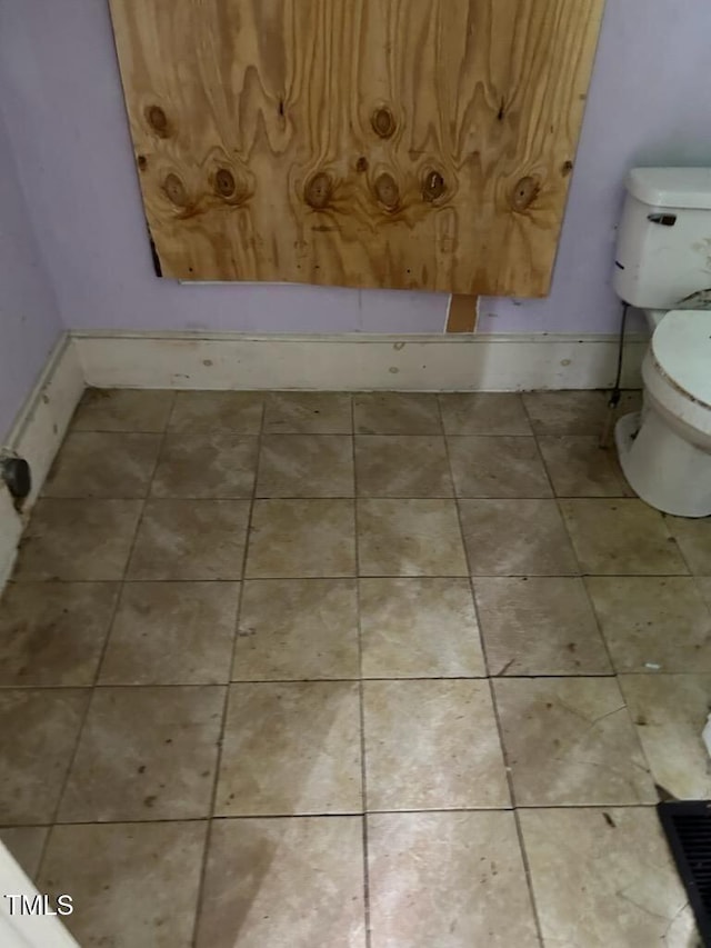 bathroom featuring tile patterned flooring, toilet, and baseboards