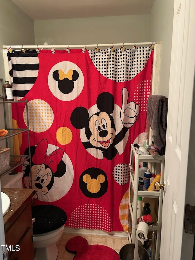 bathroom featuring toilet, a shower with shower curtain, and vanity