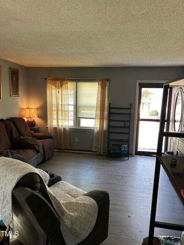 living area with a healthy amount of sunlight, a textured ceiling, and hardwood / wood-style floors