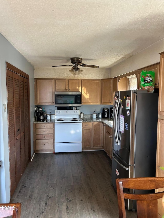 kitchen with dark wood-style floors, ceiling fan, appliances with stainless steel finishes, and a textured ceiling