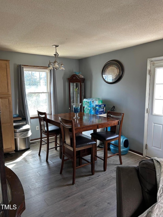 dining room with dark wood-style flooring, a textured ceiling, and baseboards