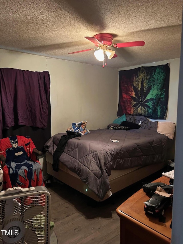 bedroom with ceiling fan, a textured ceiling, and wood finished floors