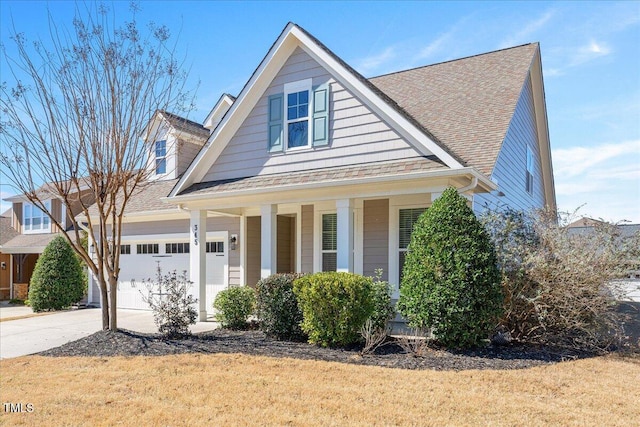 view of front of property featuring a porch, a garage, driveway, and roof with shingles