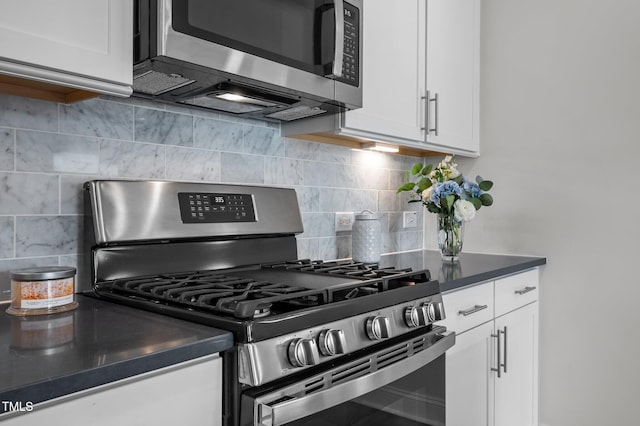 kitchen featuring dark countertops, white cabinets, backsplash, and appliances with stainless steel finishes