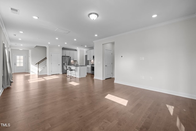 unfurnished living room with visible vents, baseboards, stairway, ornamental molding, and wood finished floors