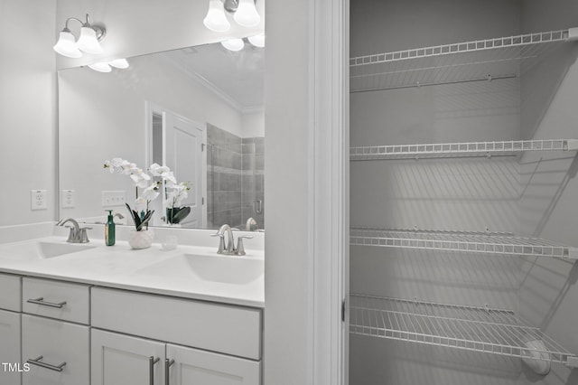 bathroom featuring a sink, a tile shower, double vanity, and crown molding