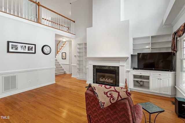 living room featuring stairs, visible vents, a premium fireplace, and wood finished floors