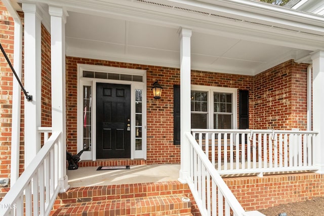 property entrance featuring covered porch and brick siding