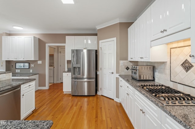 kitchen featuring a toaster, white cabinets, appliances with stainless steel finishes, ornamental molding, and light wood finished floors