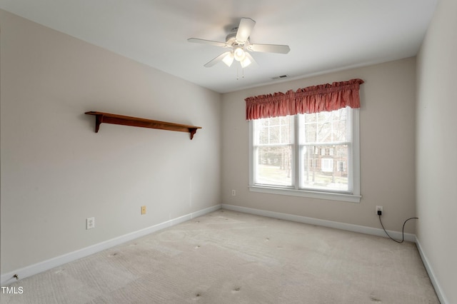 spare room with baseboards, ceiling fan, visible vents, and light colored carpet