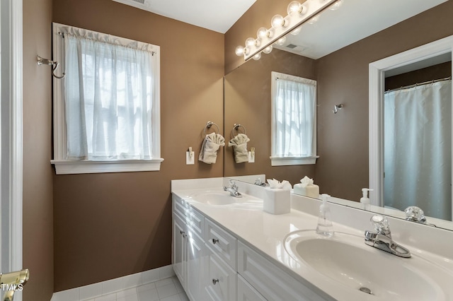 full bathroom with double vanity, tile patterned flooring, a sink, and baseboards