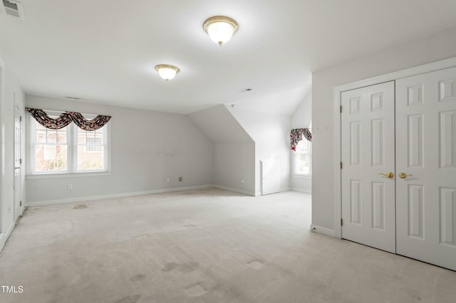 additional living space with visible vents, a wealth of natural light, and light colored carpet