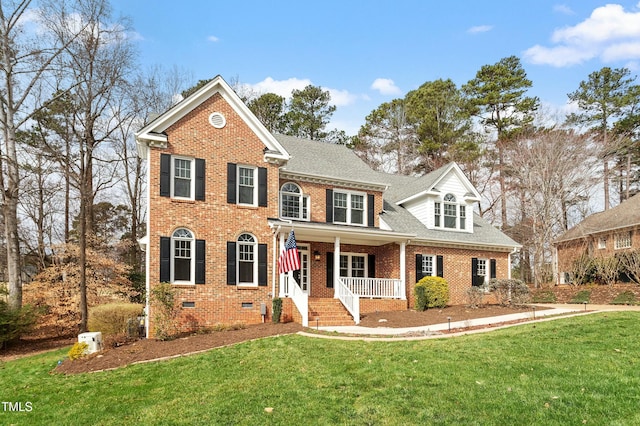 view of front of home with crawl space, brick siding, covered porch, and a front yard