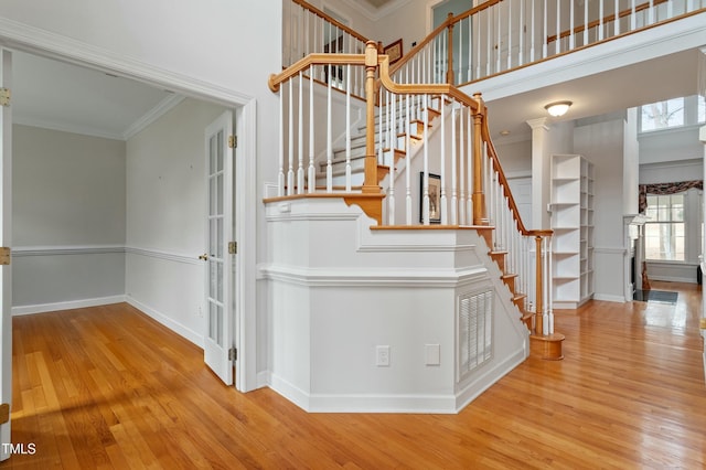 stairs with wood finished floors, visible vents, baseboards, ornamental molding, and decorative columns