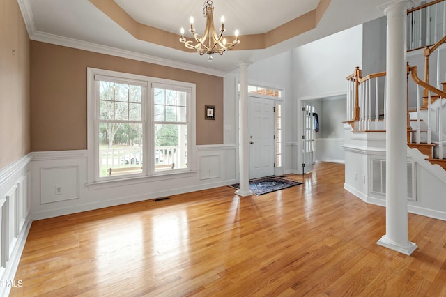 foyer entrance featuring ornate columns, stairs, visible vents, and a tray ceiling