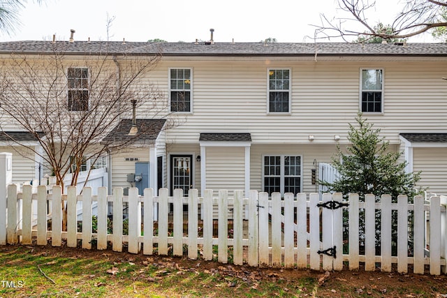 view of front of house featuring a shingled roof and a fenced front yard