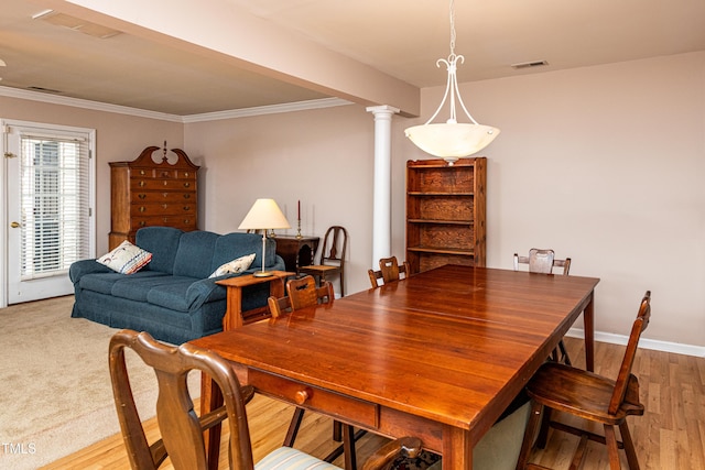 dining room with crown molding, light wood finished floors, visible vents, and ornate columns