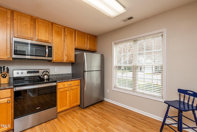 kitchen featuring stainless steel appliances, visible vents, baseboards, light wood-style floors, and brown cabinets