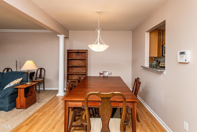 dining room with ornate columns, baseboards, and light wood finished floors