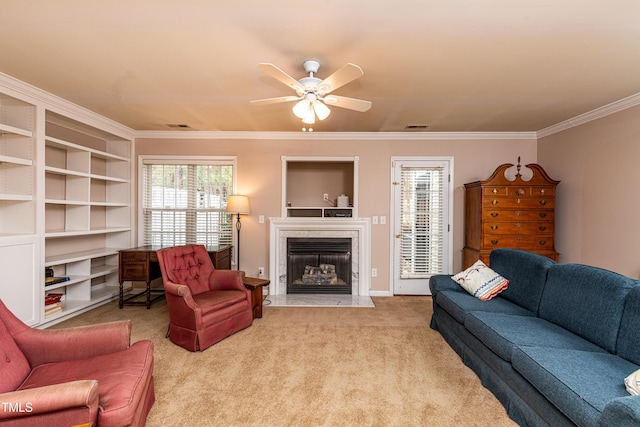 living area with ceiling fan, a high end fireplace, visible vents, carpet, and crown molding