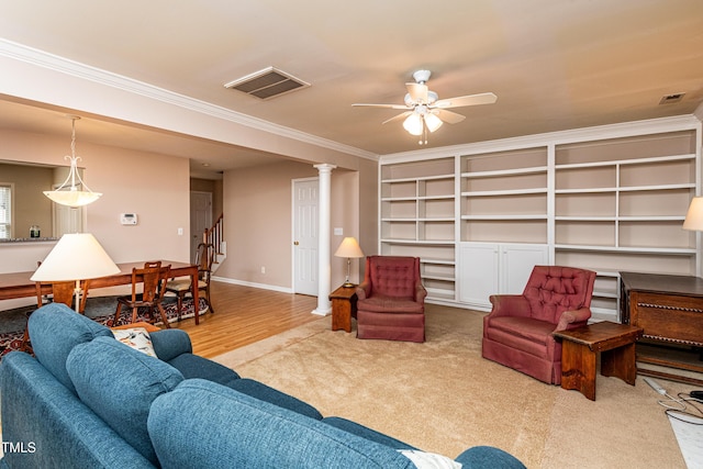 carpeted living area featuring crown molding, visible vents, and a ceiling fan