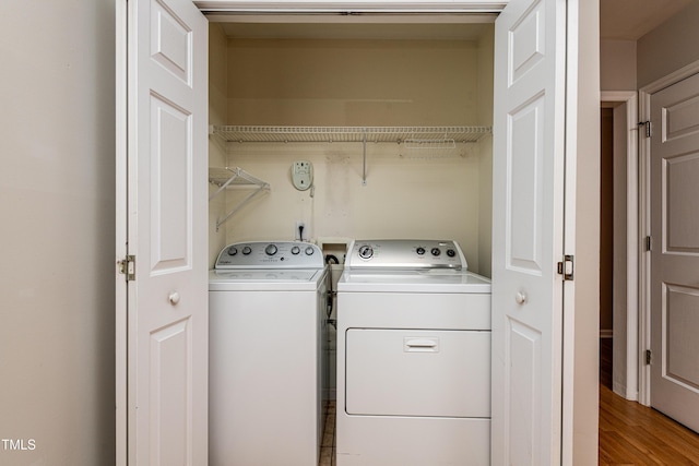 clothes washing area with light wood-style floors, washer and dryer, and laundry area