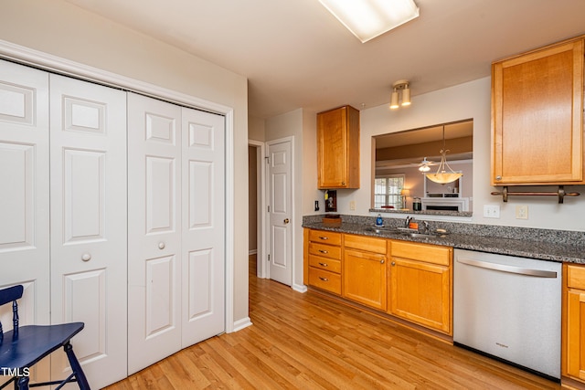 kitchen featuring a sink, light wood-style floors, dark stone counters, and stainless steel dishwasher