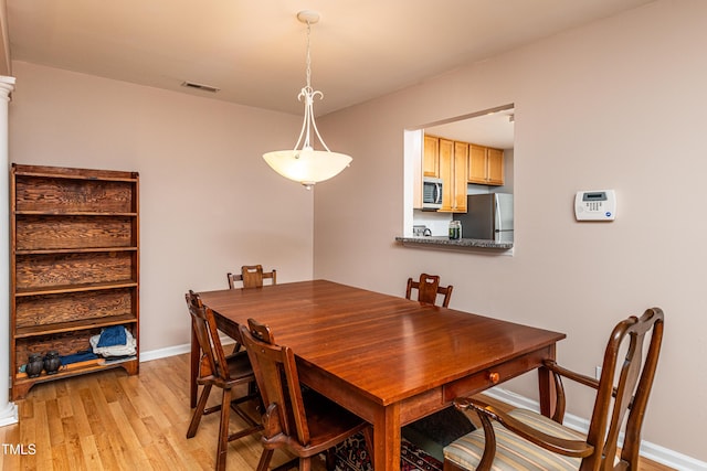 dining area featuring light wood-type flooring, visible vents, and baseboards