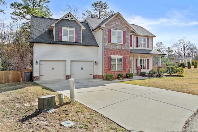 craftsman-style home with roof with shingles, a front yard, fence, a garage, and driveway