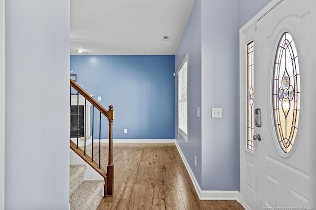 entrance foyer featuring stairs, wood finished floors, a wealth of natural light, and baseboards