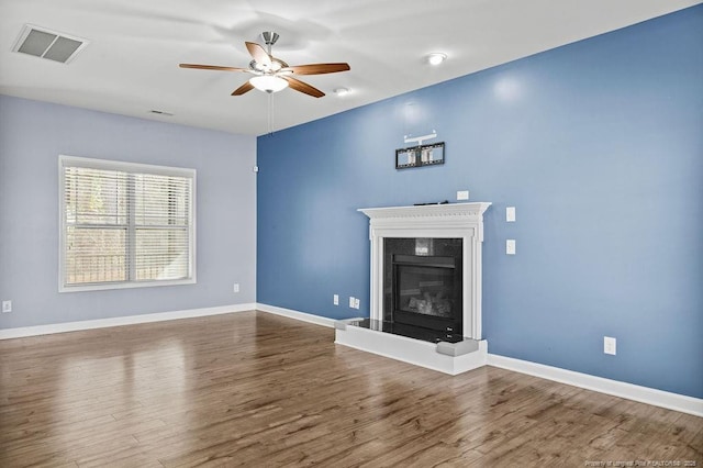 unfurnished living room featuring baseboards, visible vents, a premium fireplace, and wood finished floors