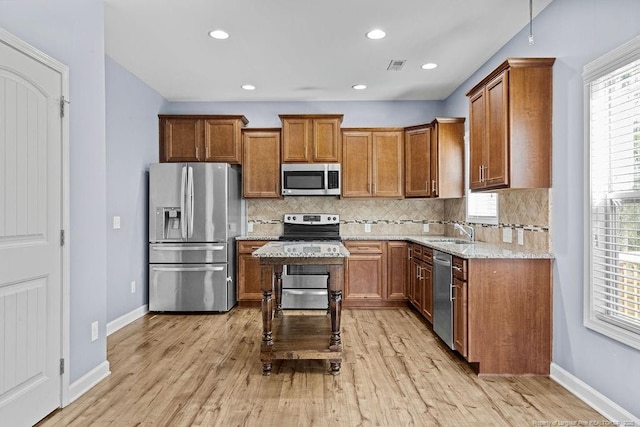 kitchen with appliances with stainless steel finishes, light wood-style flooring, visible vents, and brown cabinets