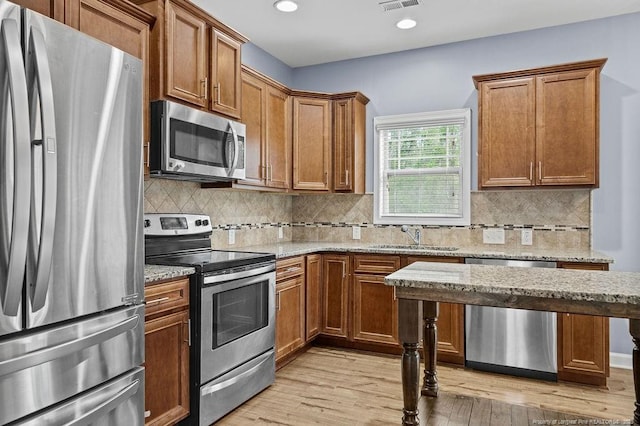 kitchen with light wood-type flooring, visible vents, stainless steel appliances, and a sink