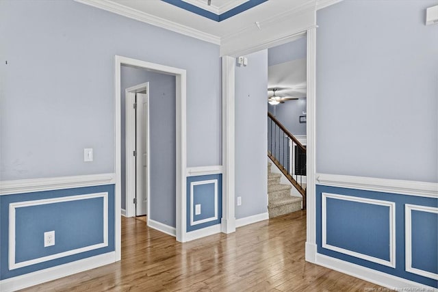 empty room featuring ceiling fan, crown molding, stairway, and wood finished floors