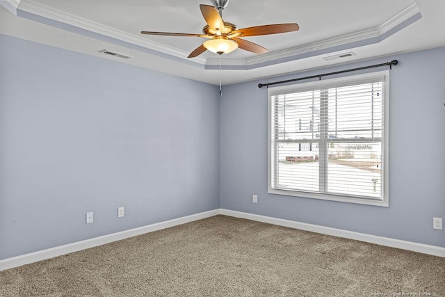 carpeted spare room with a tray ceiling, crown molding, baseboards, and ceiling fan