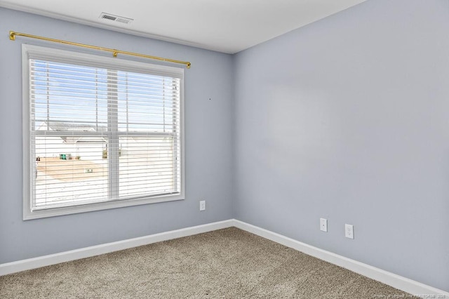 spare room with carpet, visible vents, plenty of natural light, and baseboards