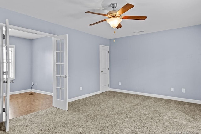 carpeted empty room with french doors, visible vents, ceiling fan, and baseboards