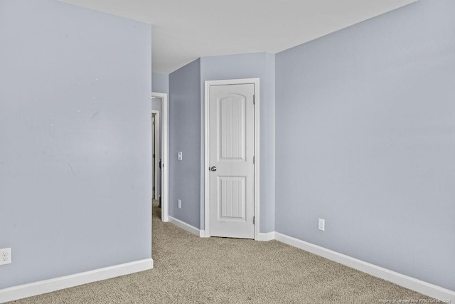 unfurnished room featuring light carpet and baseboards