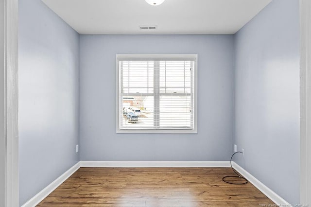 unfurnished room with visible vents, baseboards, and wood finished floors