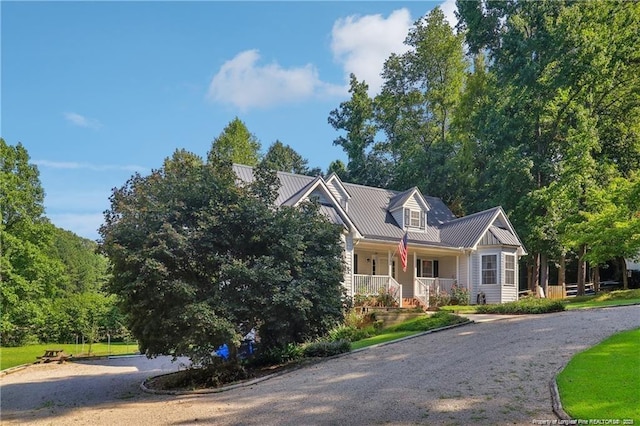 cape cod-style house with driveway, covered porch, and metal roof