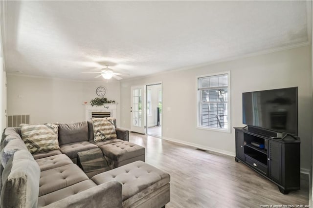 living room with light wood finished floors, ornamental molding, a fireplace, and baseboards