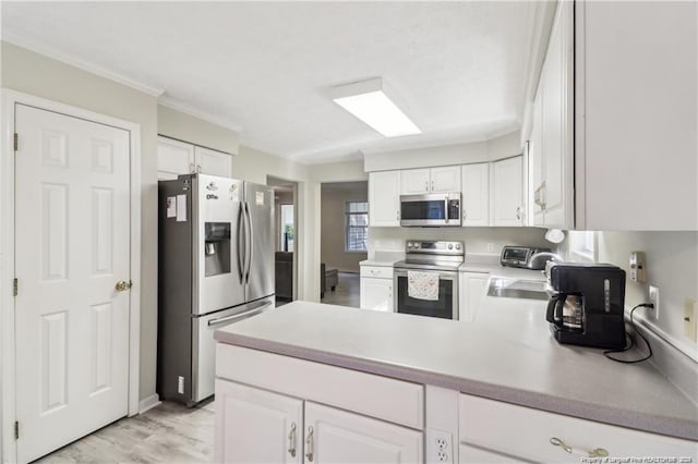 kitchen featuring light countertops, appliances with stainless steel finishes, white cabinets, a sink, and a peninsula