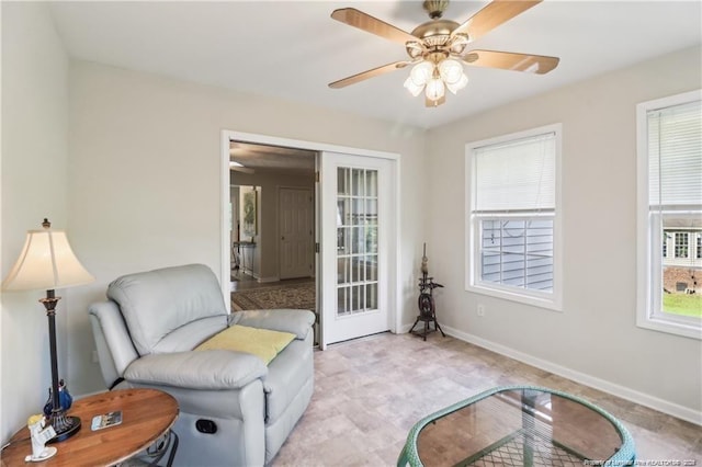 living area featuring a ceiling fan and baseboards